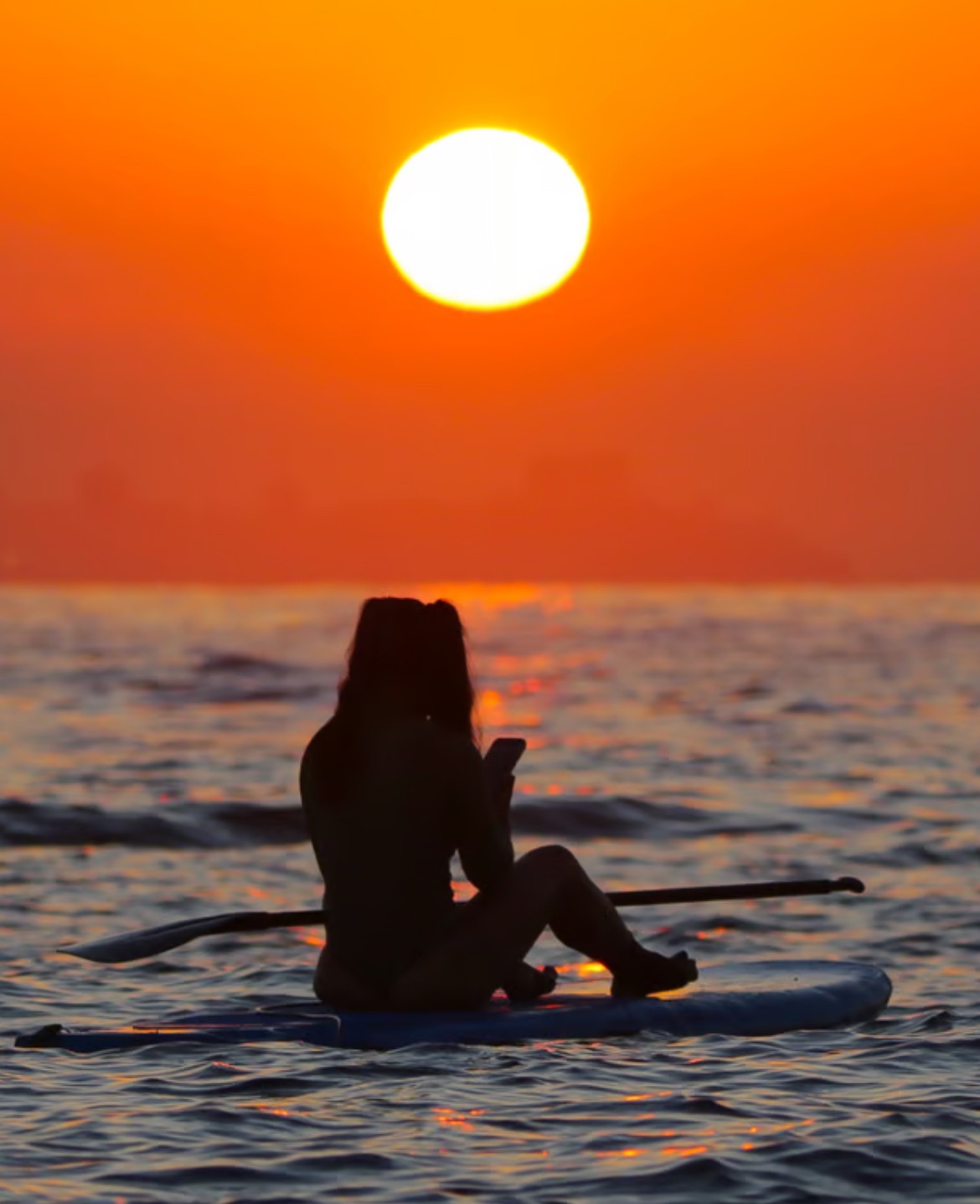 Silhueta em stand up paddle observando o pôr do sol